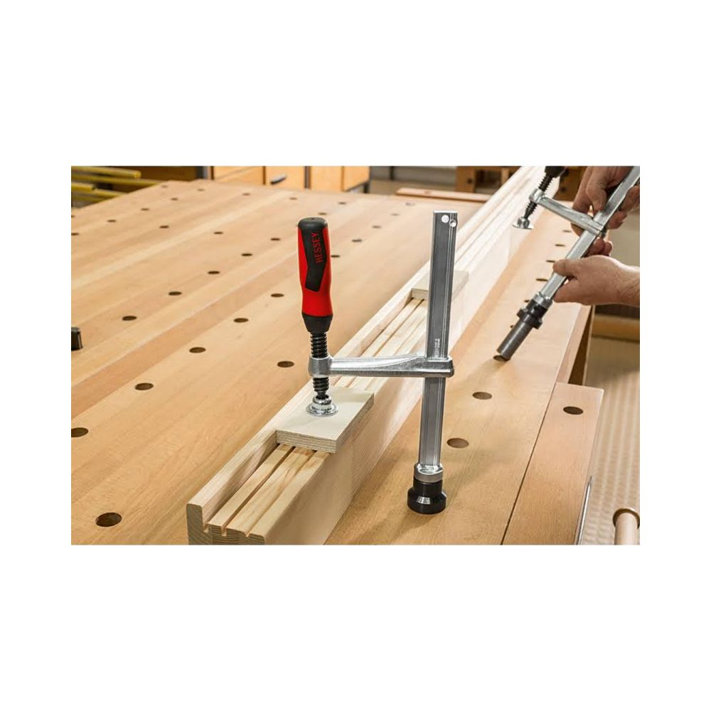 Ein Holztisch mit zwei Zwingen, die Holzstücke halten.