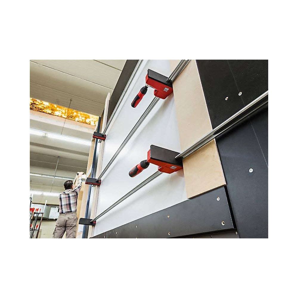 Mężczyzna w koszuli w kratę używa czerwono-czarnych ścisków na białym panelu.