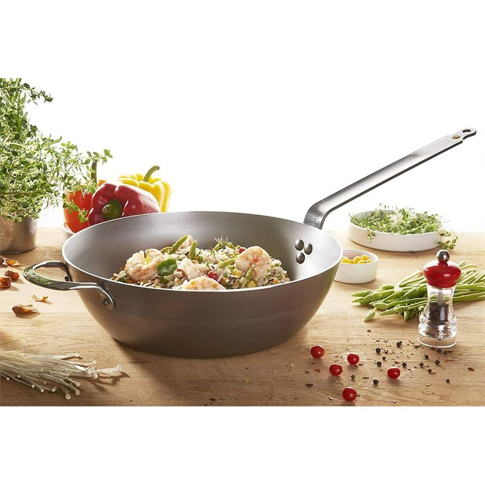 Ein Wok mit Garnelen, Reis und Gemüse, daneben Paprika, Kräuter und Gewürze.
