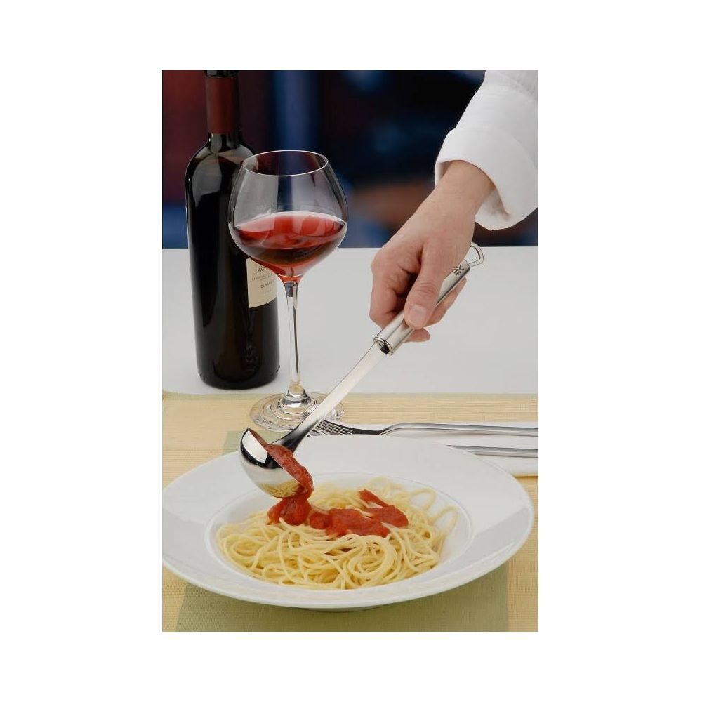 Sos jest nalewany na spaghetti na talerzu za pomocą chochli.