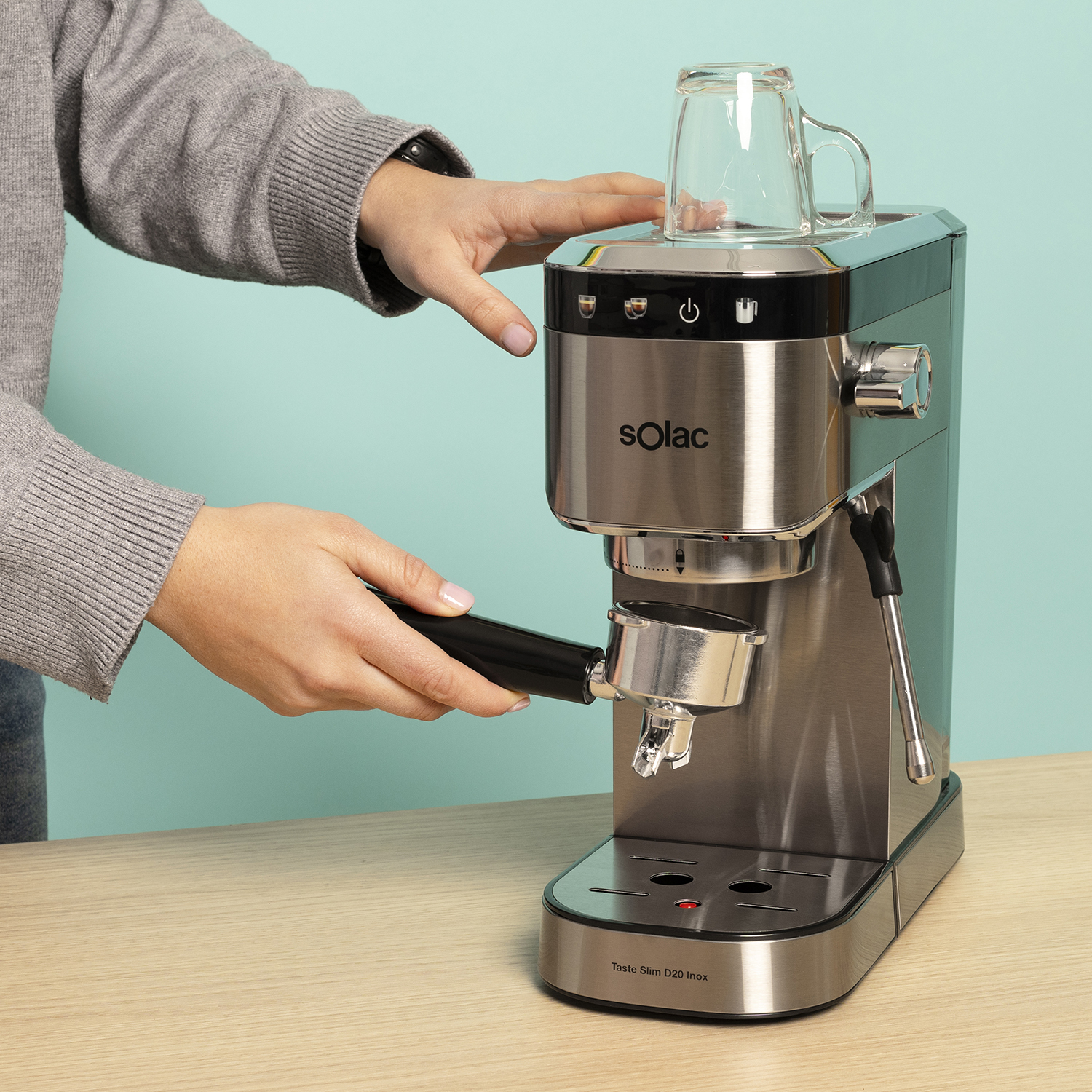 Una persona opera una máquina de espresso plateada con un portafiltro.