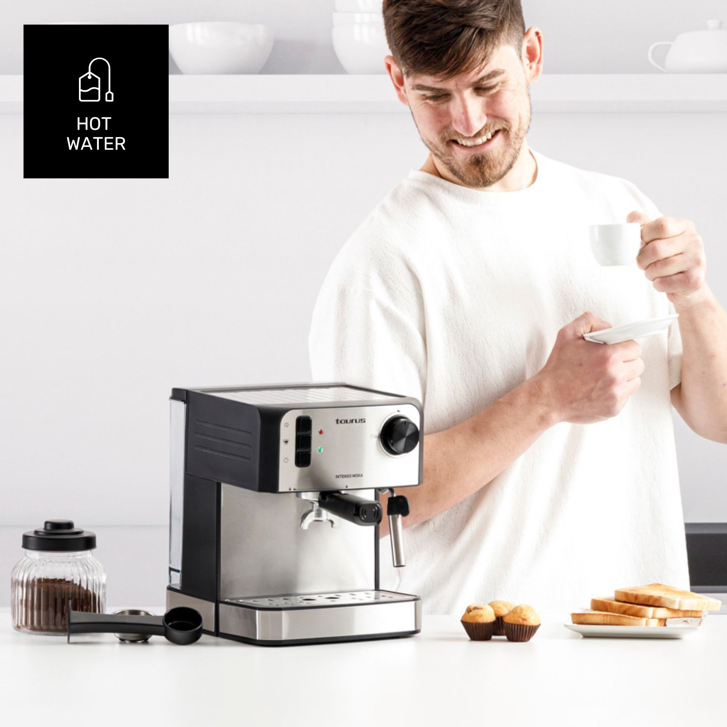 Hombre con taza de café, cafetera, muffins y tostadas sobre mesa blanca.