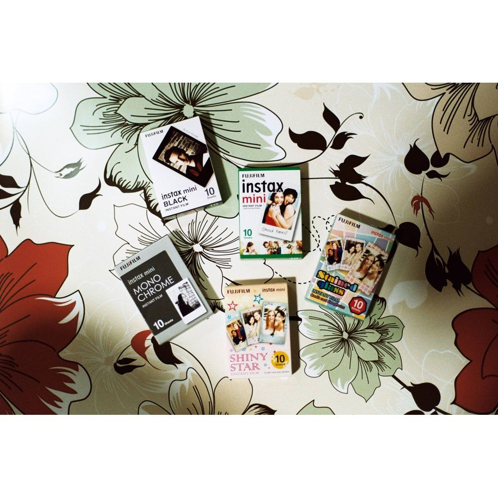 Cinco paquetes de película Fujifilm Instax Mini sobre fondo floral.
