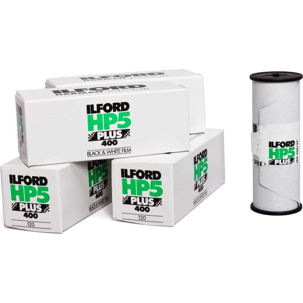 Varias cajas de película Ilford HP5 Plus 400 y un rollo de película sobre fondo blanco.