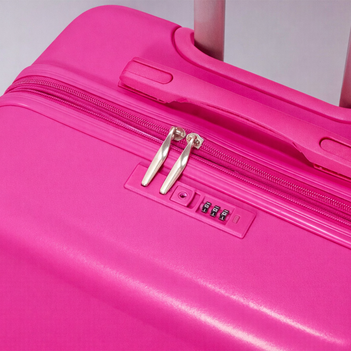 Primer plano de la superficie de una maleta rosa brillante con cremallera, asa y candado.