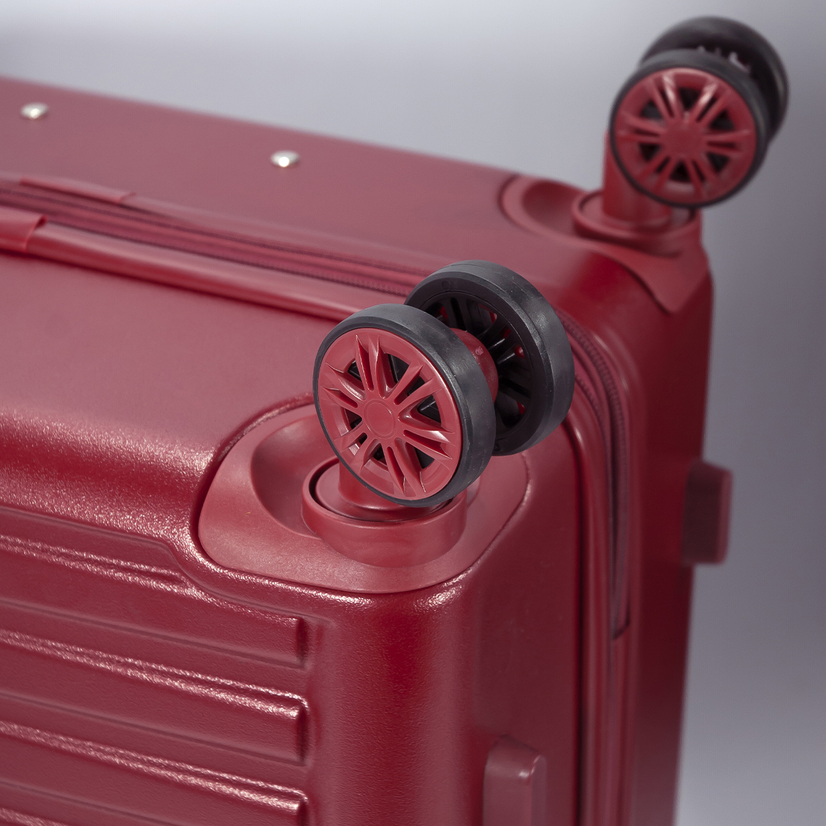Maleta roja mostrando dos ruedas. Las ruedas son negras con radios rojos.