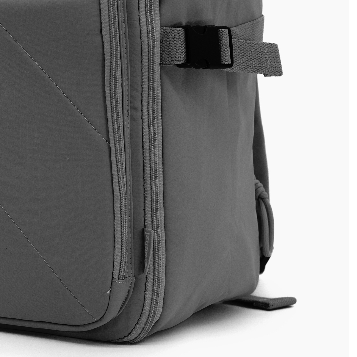 Mochila gris con cremallera y hebilla, vista de cerca.