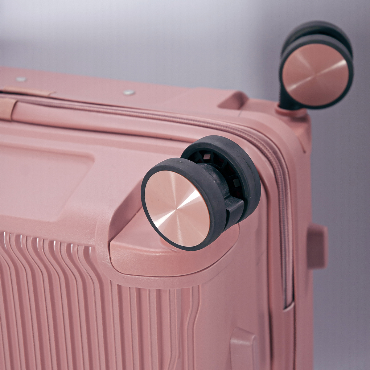Una maleta rosa con dos ruedas y detalles metálicos.