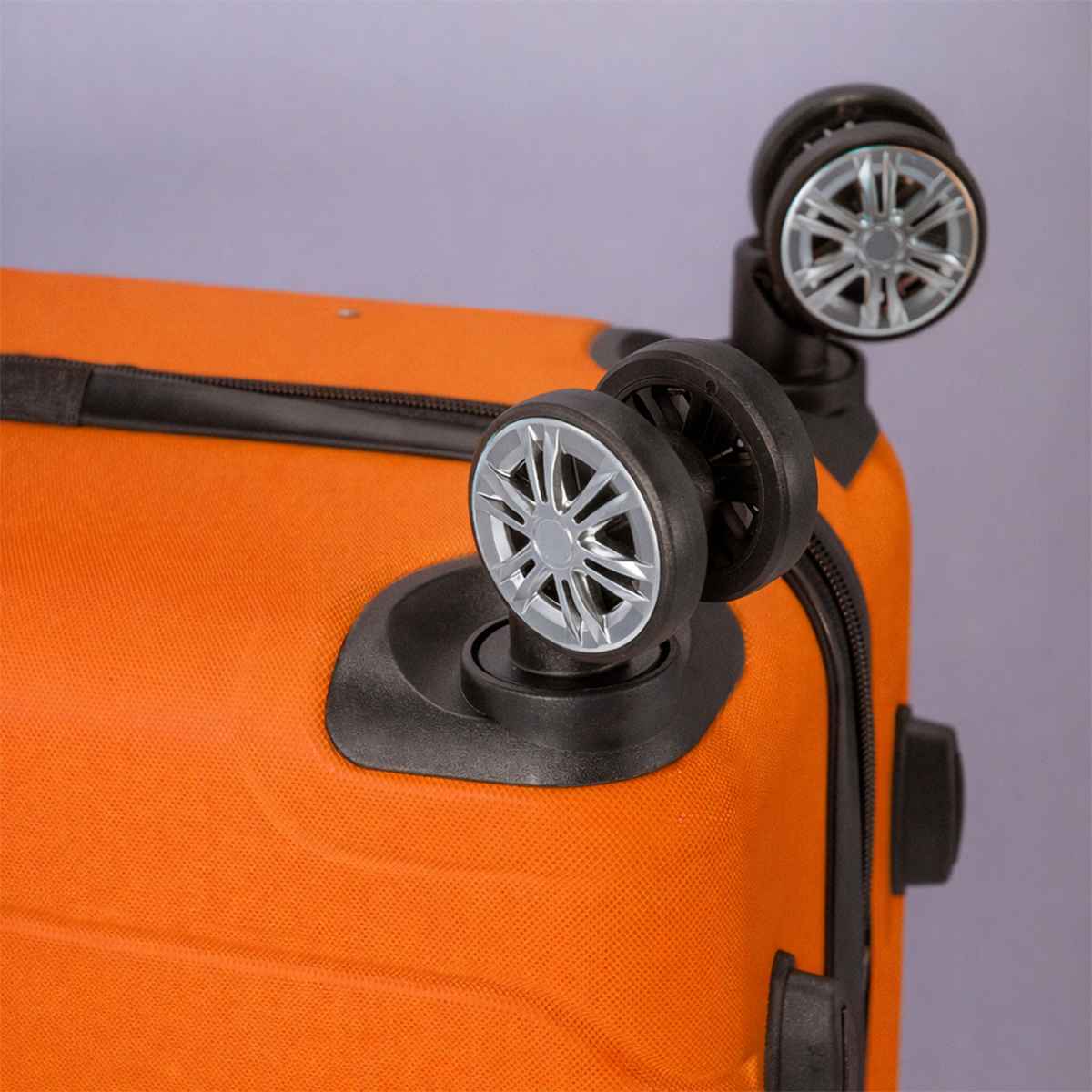 Maleta naranja con cuatro ruedas. Primer plano de las ruedas y la cremallera.