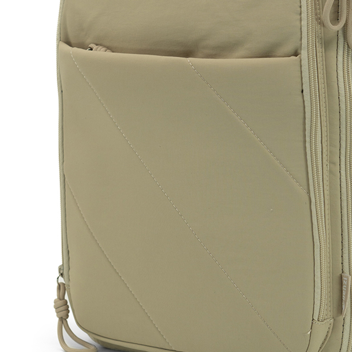 Bolso beige con costuras diagonales y detalle de cremallera.
