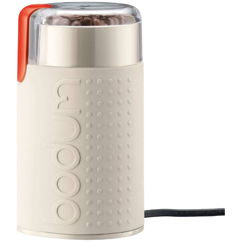 Ein cremefarbener elektrischer Kaffeemühle mit orangefarbenem Akzent und Kaffeebohnen.