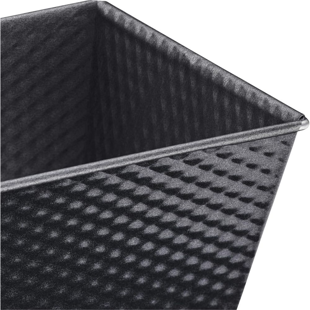 Szara forma do chleba z wzorem romboidalnym i żebrowanym brzegiem.