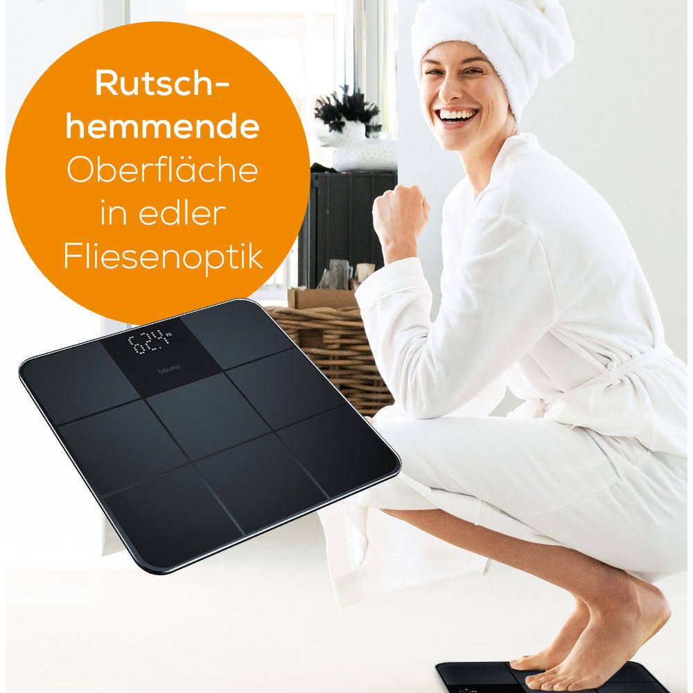 Donna in vestaglia ride accanto a bilancia digitale effetto piastrella.