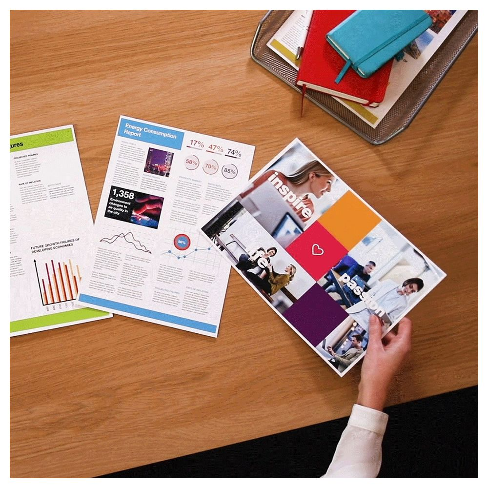 Biurko z raportami i notatnikami. Ręka trzyma broszurę.