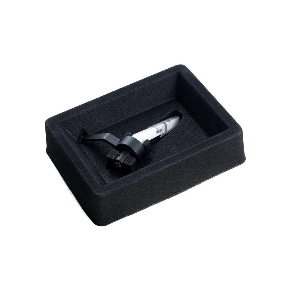 Une cellule phono blanche avec bras noir dans un insert en mousse noire.