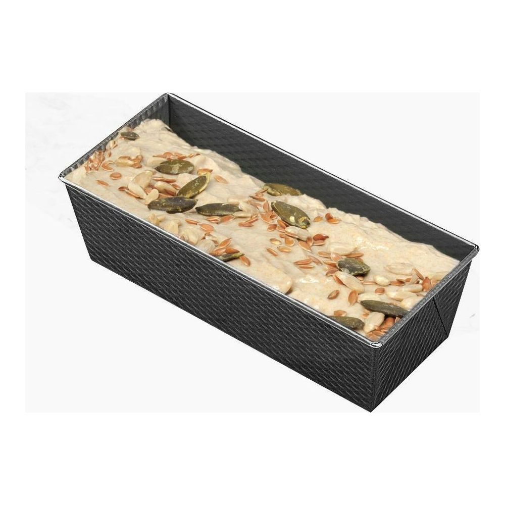 Ein Brotlaib aus Teig mit Kürbiskernen und Leinsamen in einer rechteckigen Backform.