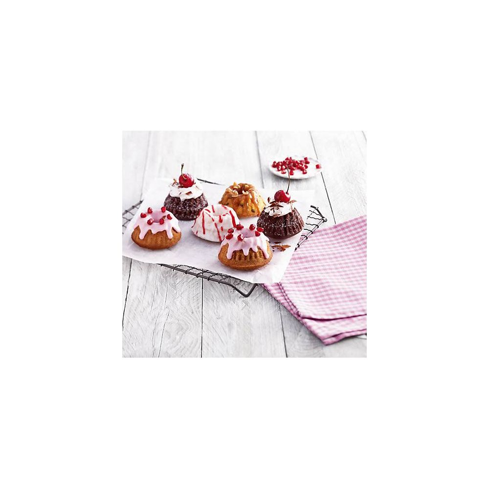 Sześć małych ciast z lukrem i owocami na kratce.