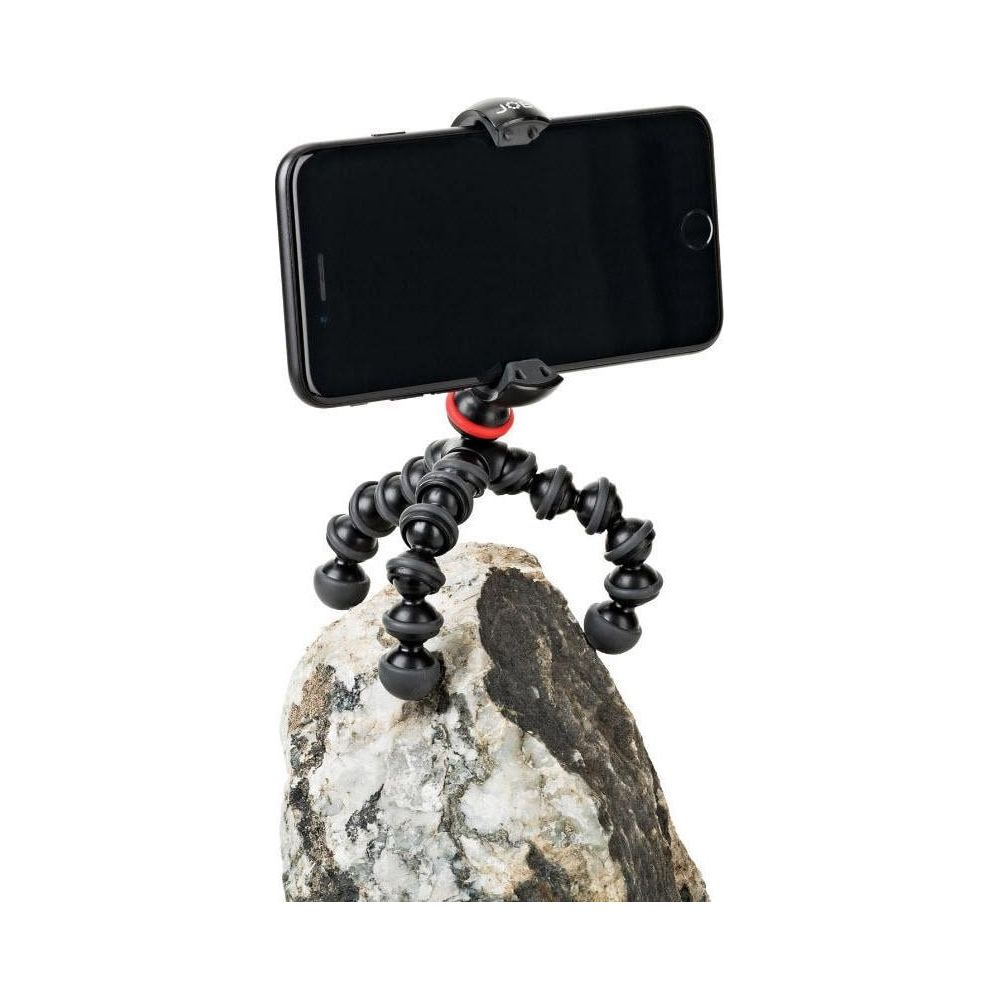 Uno smartphone nero è montato su un treppiede flessibile attaccato a una roccia.