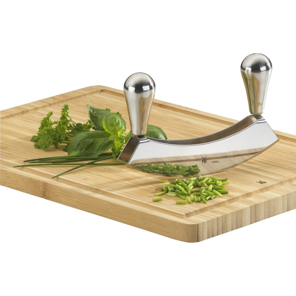 Ein halbrunder Gemüseschneider mit zwei Griffen auf einem Holzschneidebrett mit Kräutern.