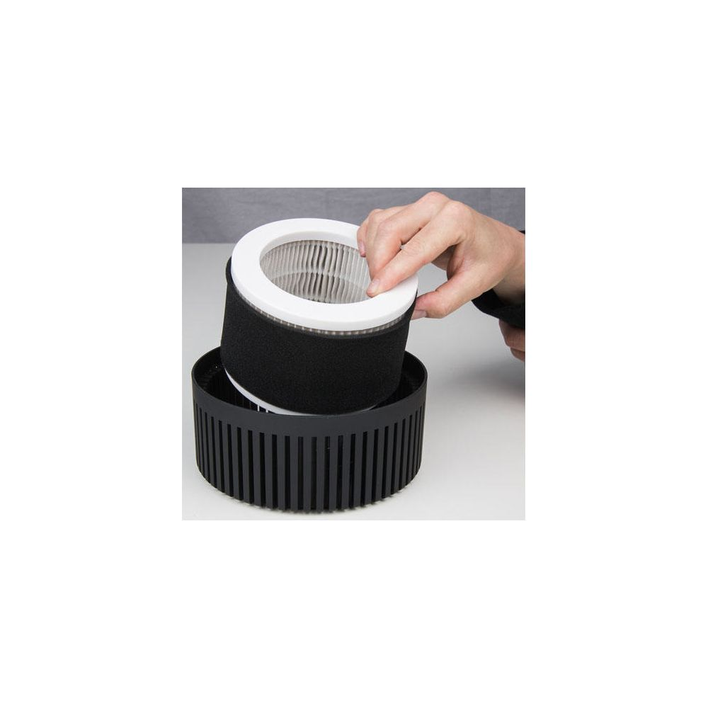 Une main tient un filtre à air au-dessus d'un boîtier de filtre noir.
