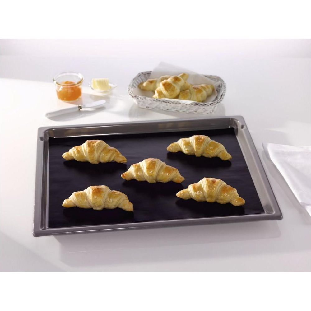 Fünf goldbraune Croissants liegen auf einer schwarzen Backmatte auf einem Blech.
