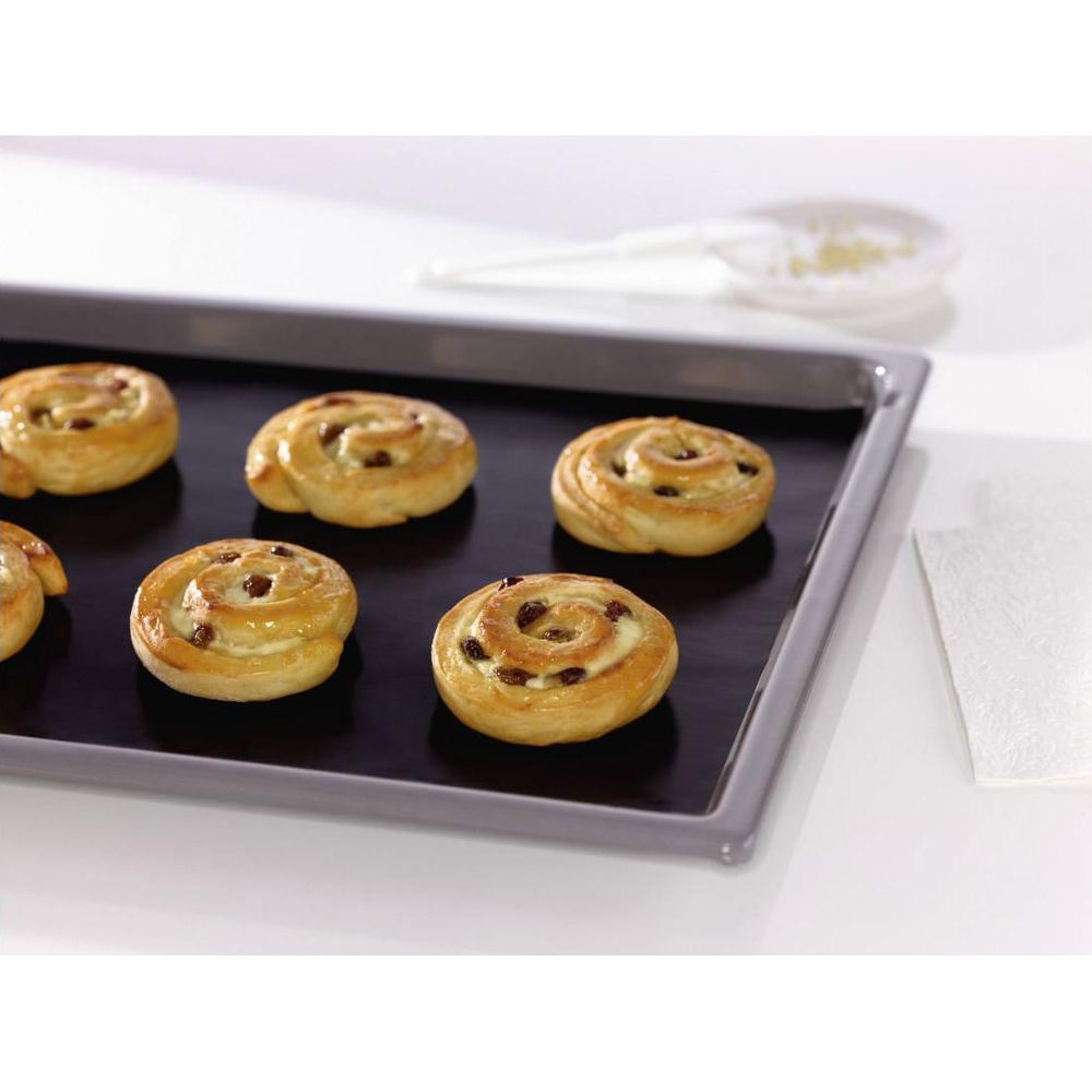 Sechs goldbraune Zimtschnecken mit Rosinen auf einem Backblech.