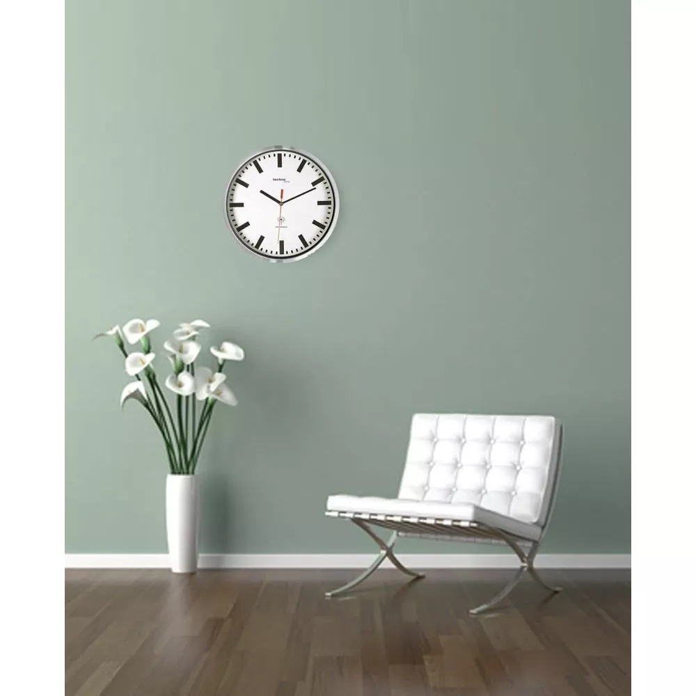Eine weiße Vase mit Blumen und ein weißer Sessel vor einer mintgrünen Wand.