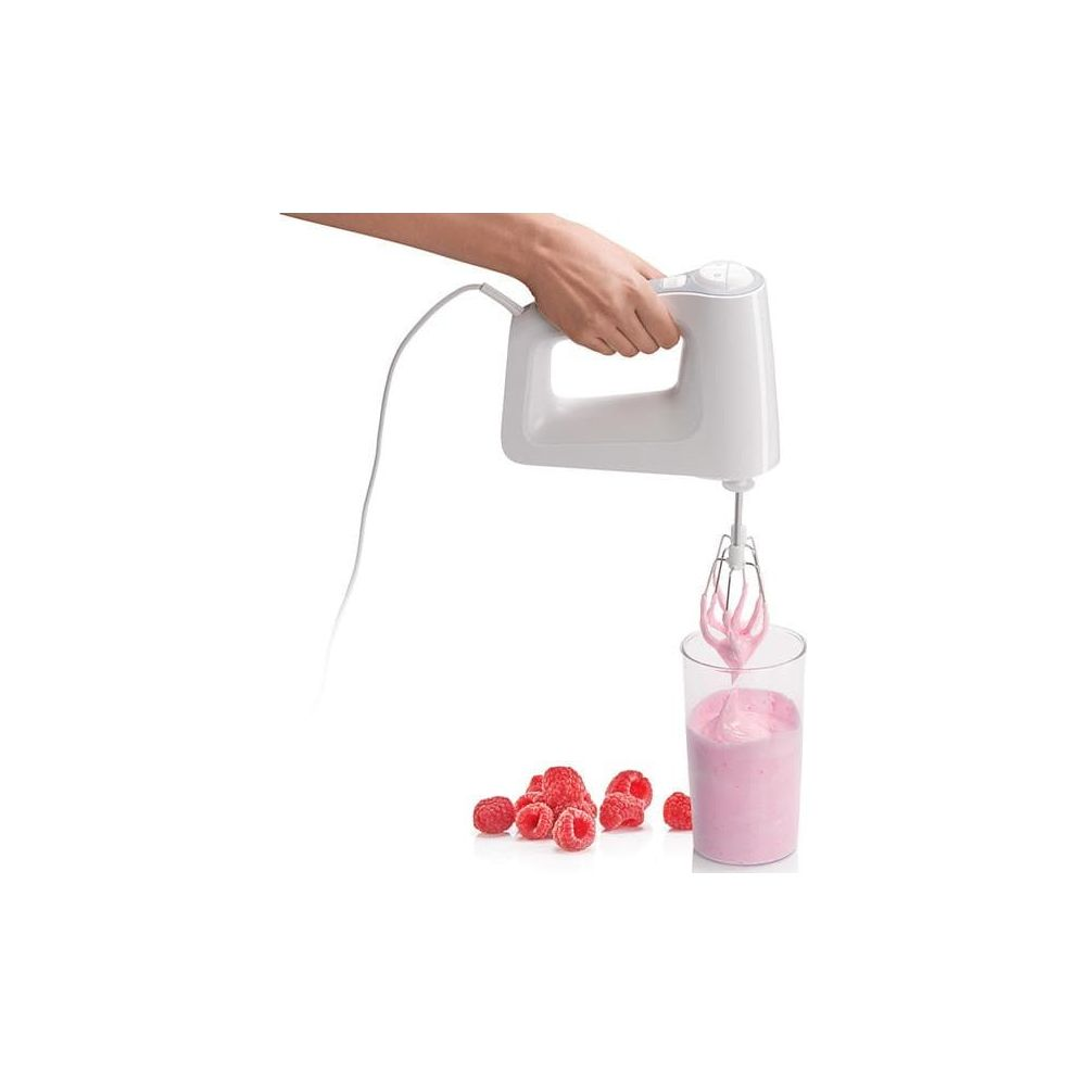 Biały mikser ręczny ubija różowy płyn w szklance. W pobliżu leżą maliny.