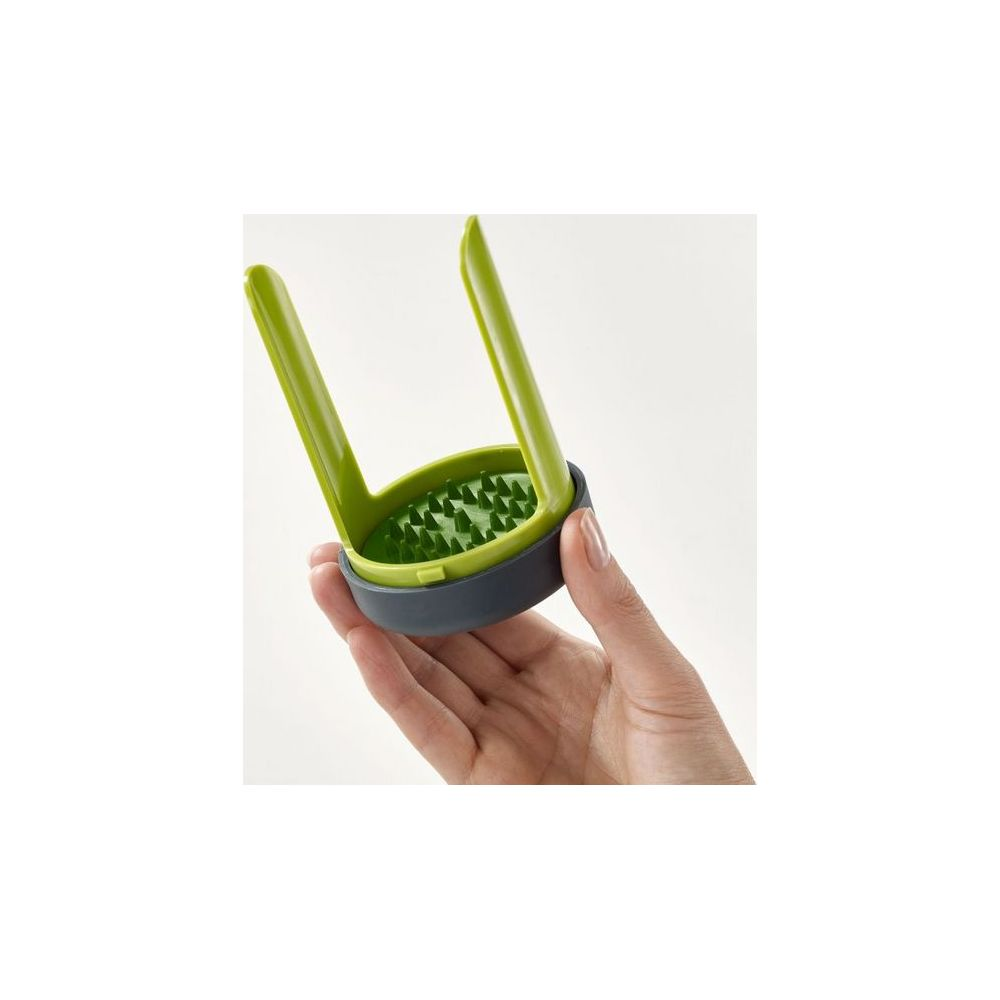 Schiacciapatate verde e grigio con denti tenuto in mano.