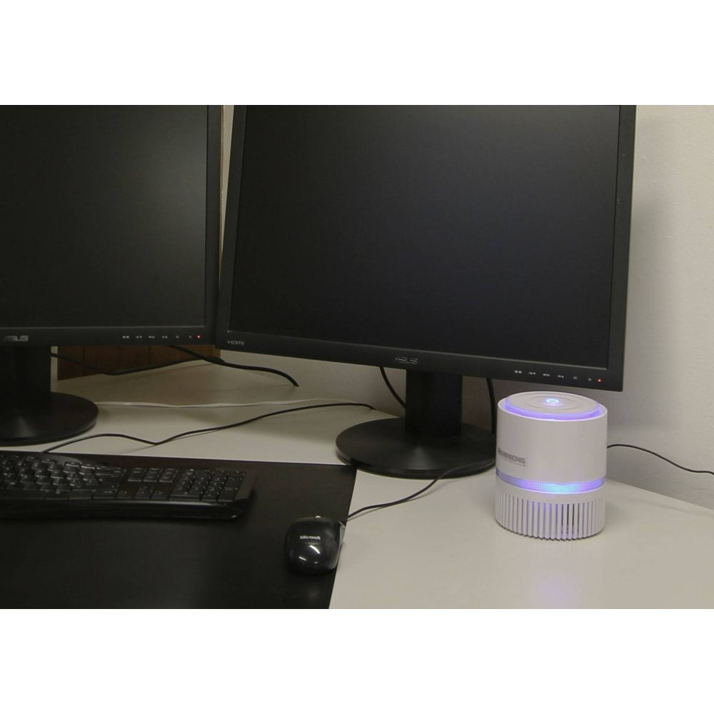Due monitor per computer, tastiera, mouse e un purificatore d'aria bianco con luci blu.
