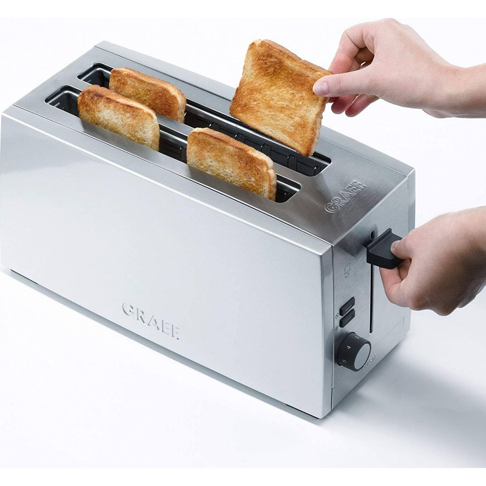 Eine Hand legt Toast in einen silbernen Toaster, während andere Toasts bereit sind.