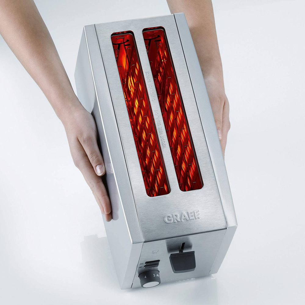 Zwei Hände halten einen silbernen Toaster mit glühenden roten Heizelementen.