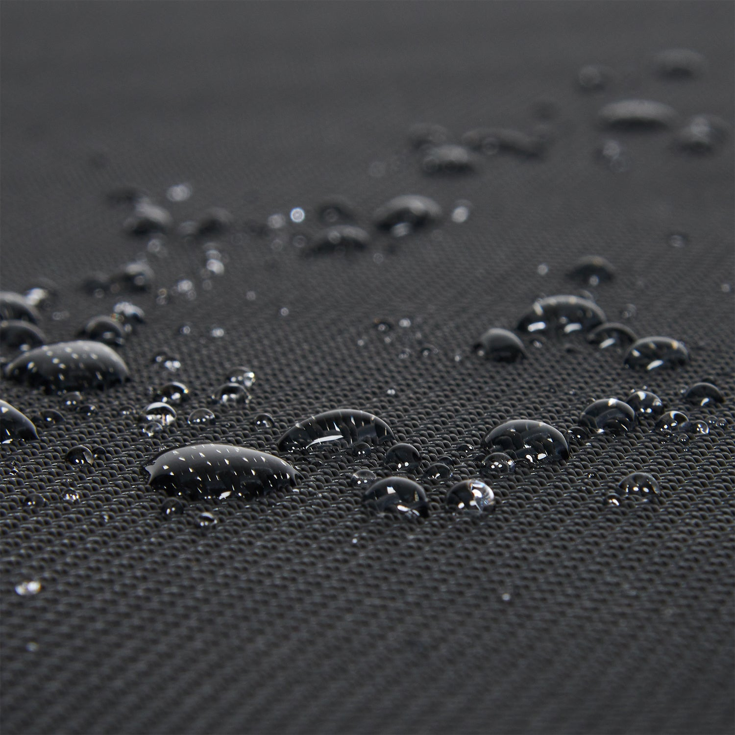 Waterdruppels op zwart textiel met zichtbaar patroon.
