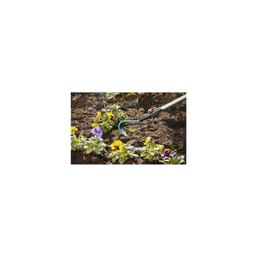 Attrezzo da giardino lavora terra accanto a fiori con fiori viola e gialli.