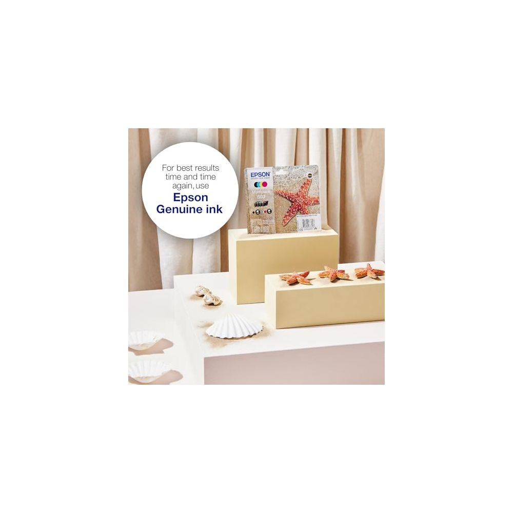 Opakowanie tuszu Epson z czerwoną rozgwiazdą na postumencie, w pobliżu rozgwiazdy i muszle.