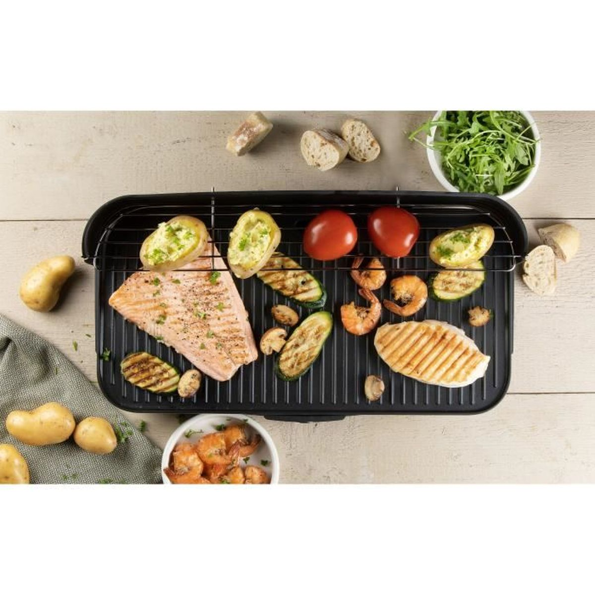 Ein Elektrogrill mit Lachs, Garnelen, Zucchini, Tomaten, Brot und Kartoffeln.