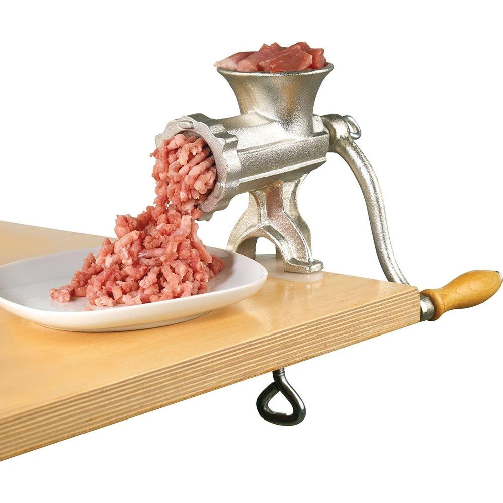 Un tritacarne metallico lavora carne su un tavolo.