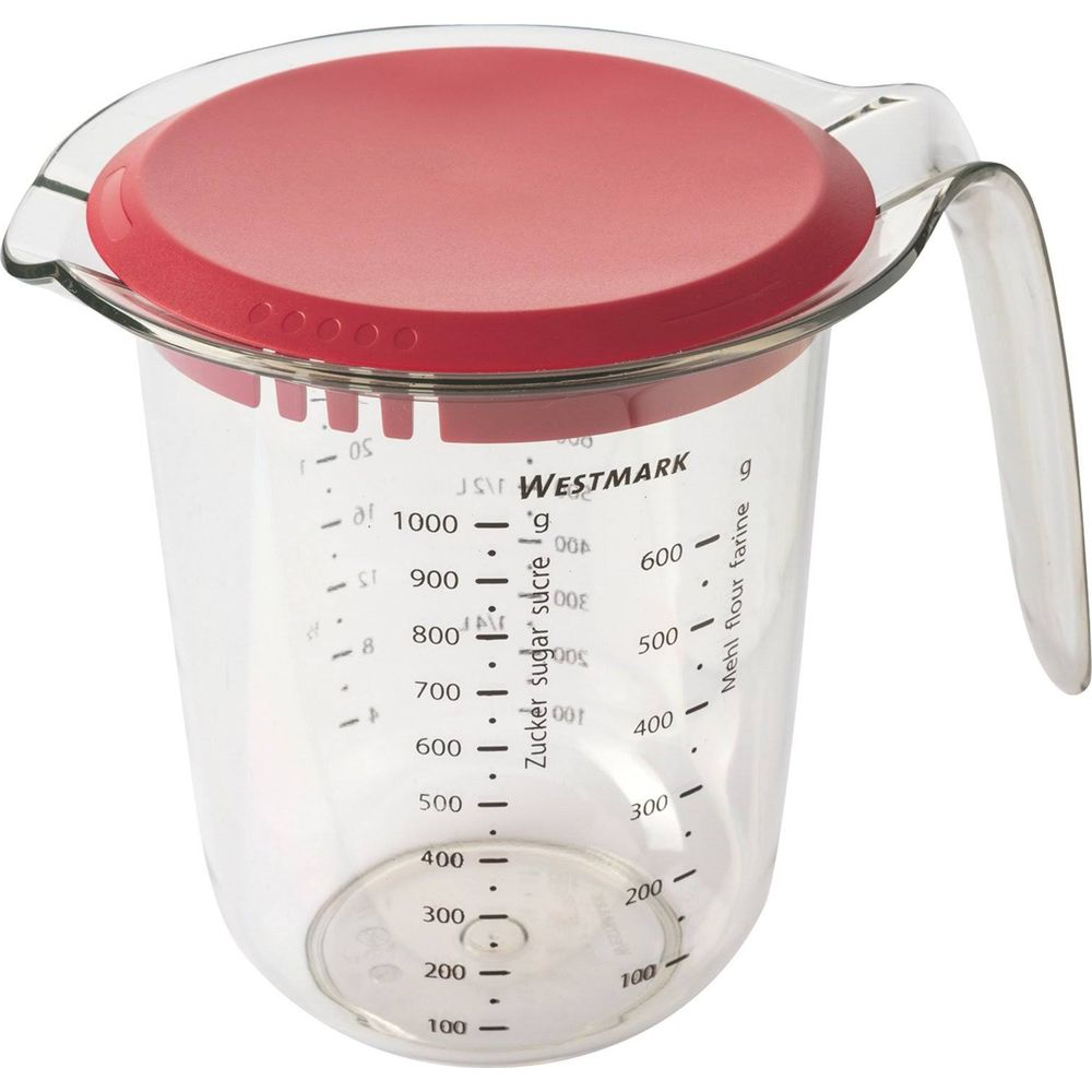 Ein transparenter Messbecher mit rotem Deckel und Griff, Messungen in Gramm und Milliliter.