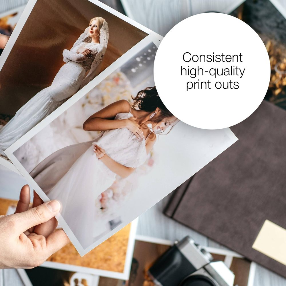 Des mains tiennent des photos de mariage de mariées. Un livre et un appareil photo sont à proximité.