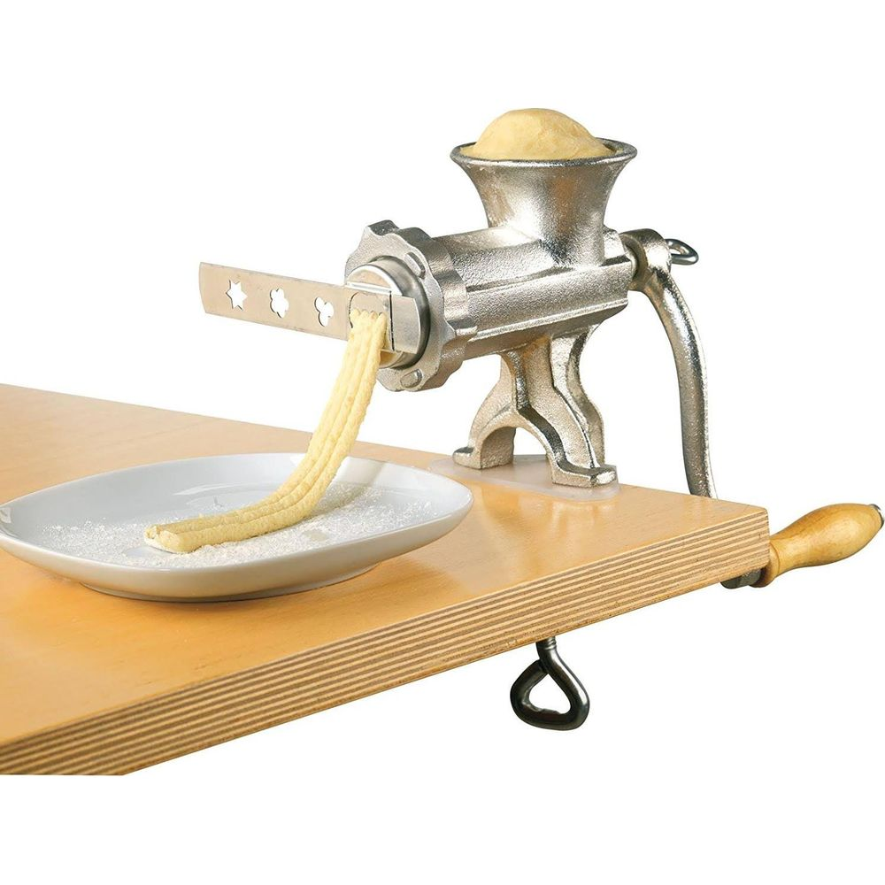 Una macchina per la pasta estrude l'impasto su un piatto con farina.