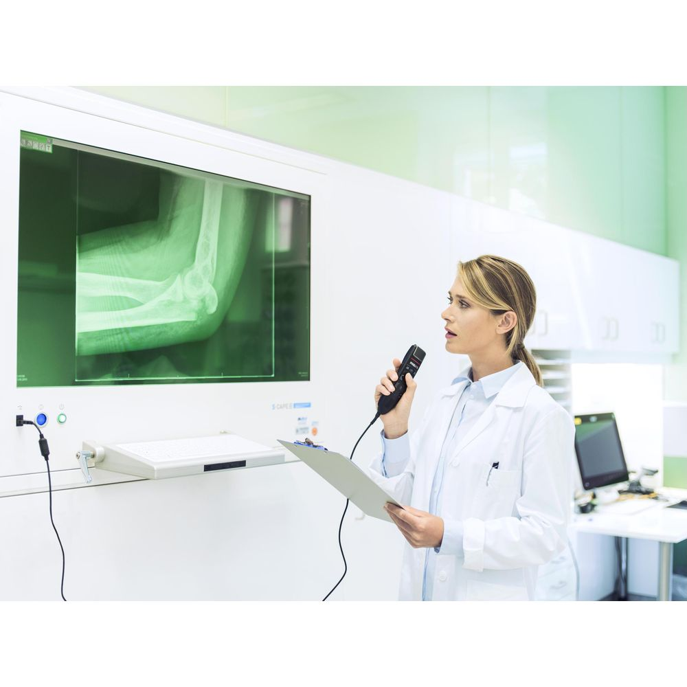 Medico con microfono e radiografia di un braccio davanti a uno schermo.