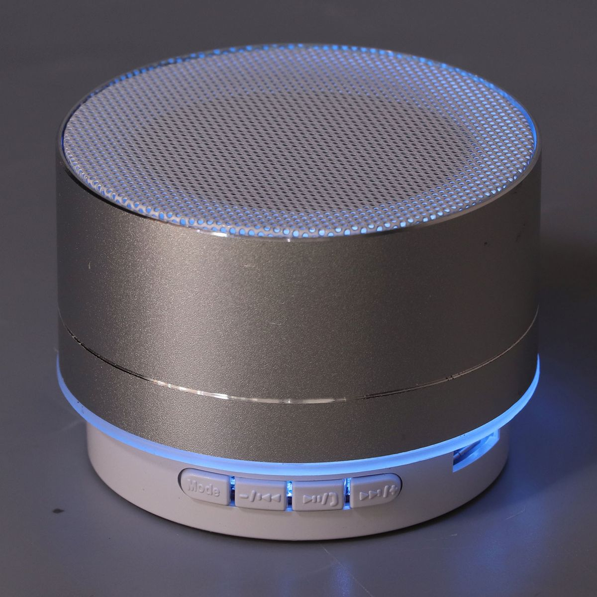Ein silberner Bluetooth-Lautsprecher mit blauer LED-Beleuchtung und Bedientasten.