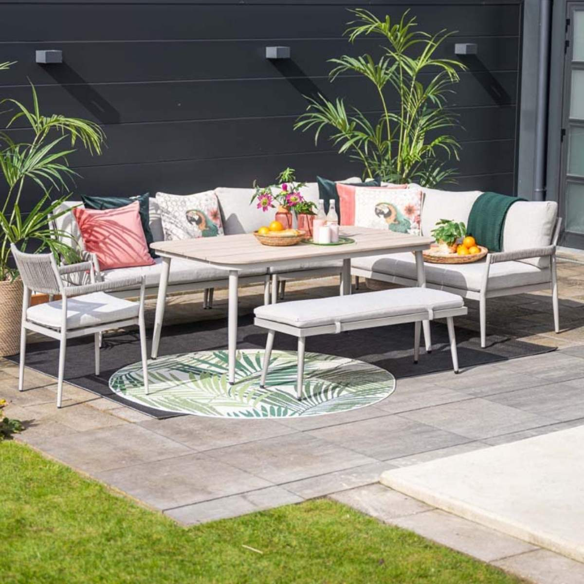 Buitenmeubelset met tafel, bank, stoelen en bankje op een terras.
