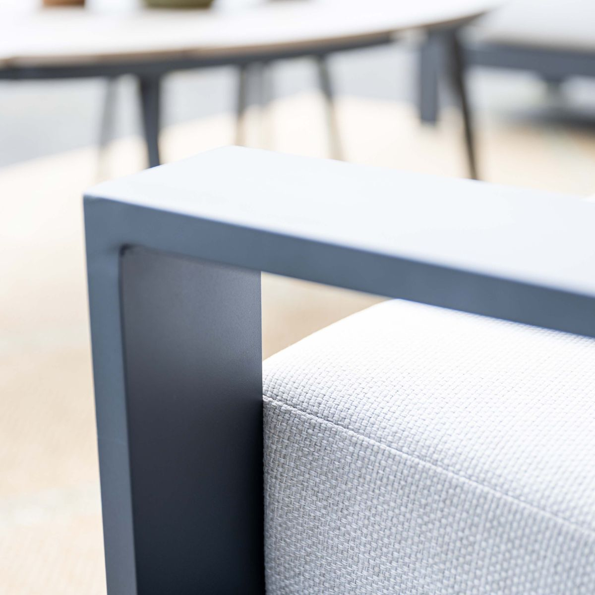 Grijs metalen frame van buitenstoel met wit kussen.