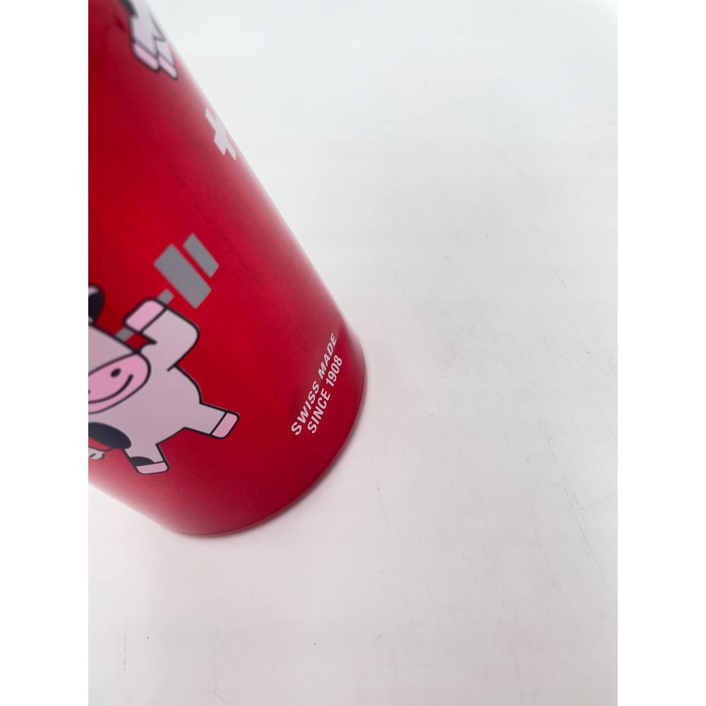 Rote Dose mit pinker Kuh und Gewichten, Swiss Made seit 1908.