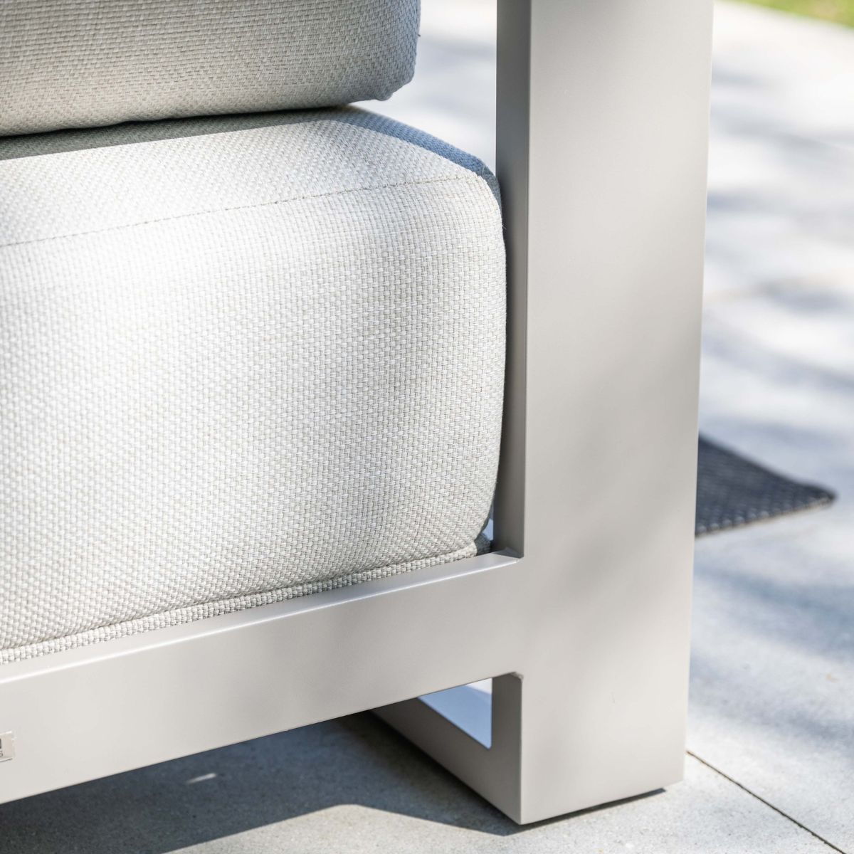 Grijze fauteuil met lichtgrijze bekleding op een stenen terrasvloer.