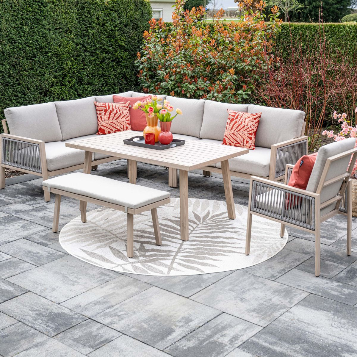 Tuin lounge set met tafel, bank, stoel en kruk op een ronde mat.