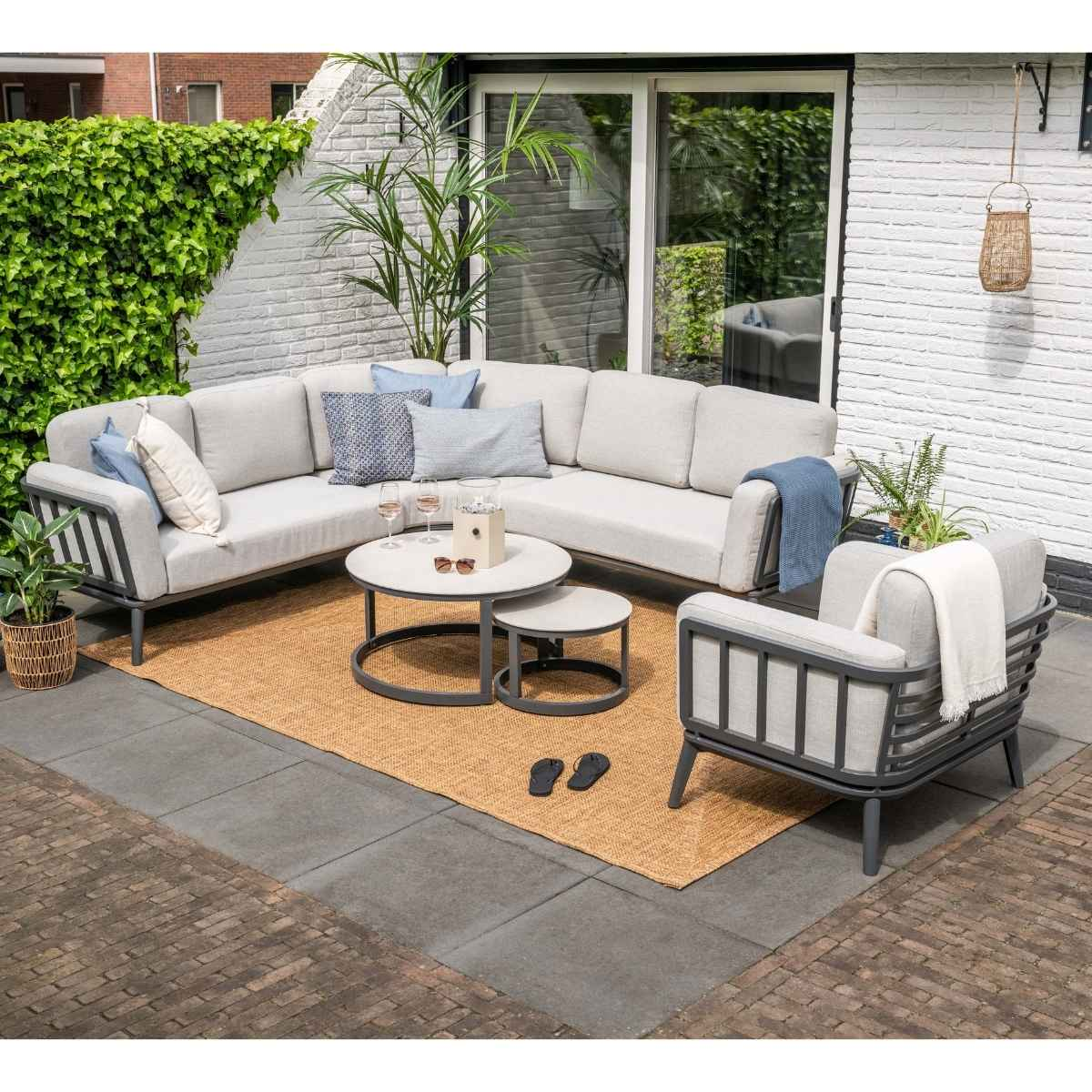Grijze buitenloungeset met salontafels op een kleed.