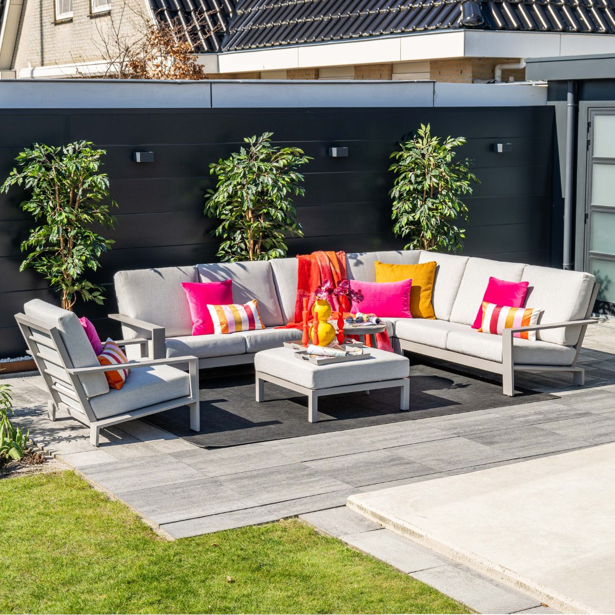 A modern grey outdoor sectional sofa with colorful cushions on a patio.