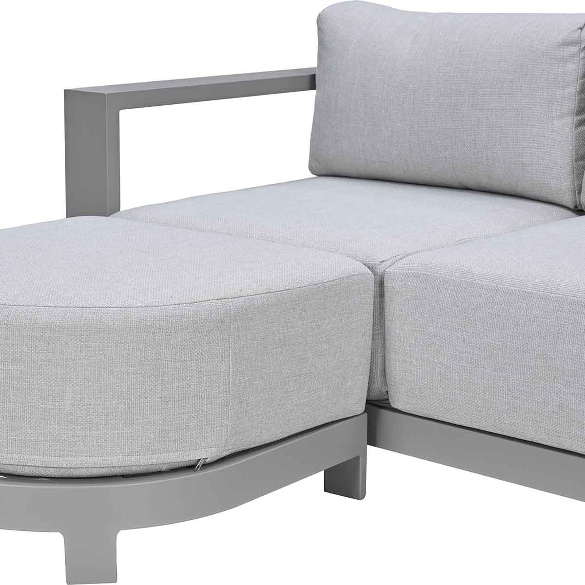 Grijze modulaire bank met armleuning en poef. Strakke lijnen, modern design.
